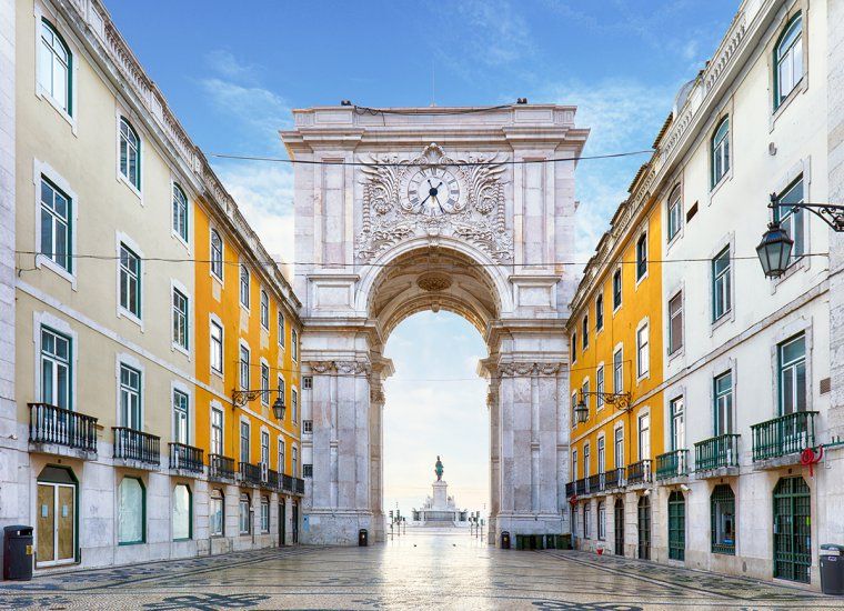 Looking down empty tiled street and through Rua Augusta Arch in Lisbon, Portugal