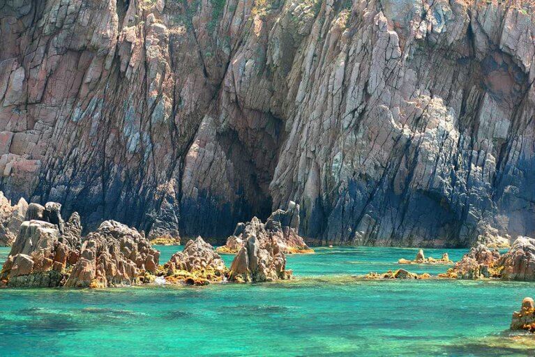 Turquoise water along the rocky cliffs in Scandola Nature Reserve in Corsica