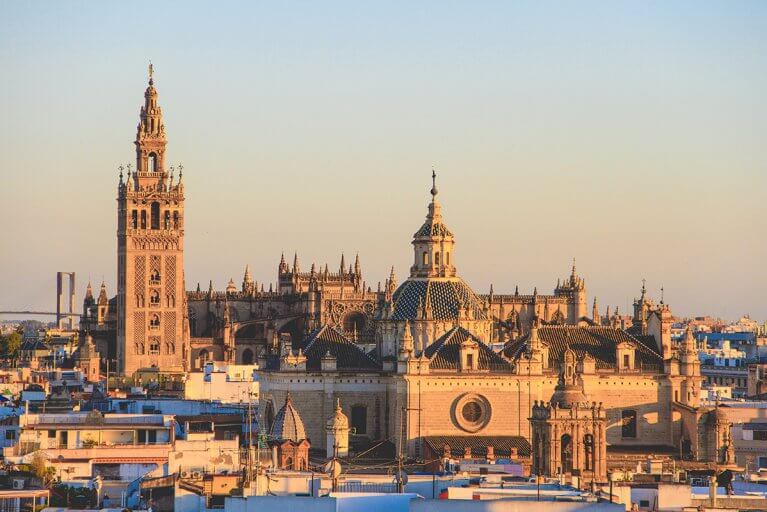 Seville cathedral and its many spires surrounded by city at sunset