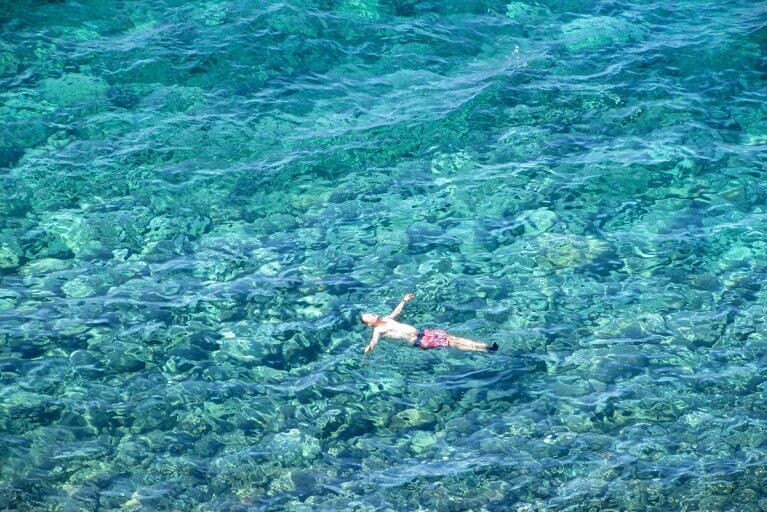 Boy floating in crystal clear waters of the Tyrrhenian Sea