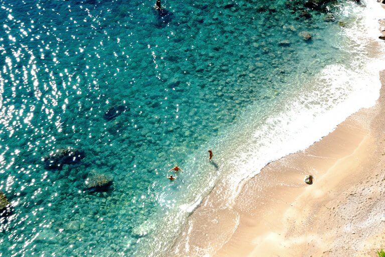 Aerial view of two people in blue water by a deserted beach during luxury Croatia trip