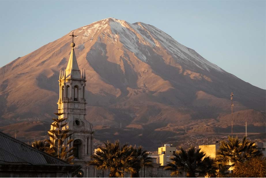 Cathedral spire and palm trees in Arequipa in front of snow capped Misti Mountain in late afternoon light
