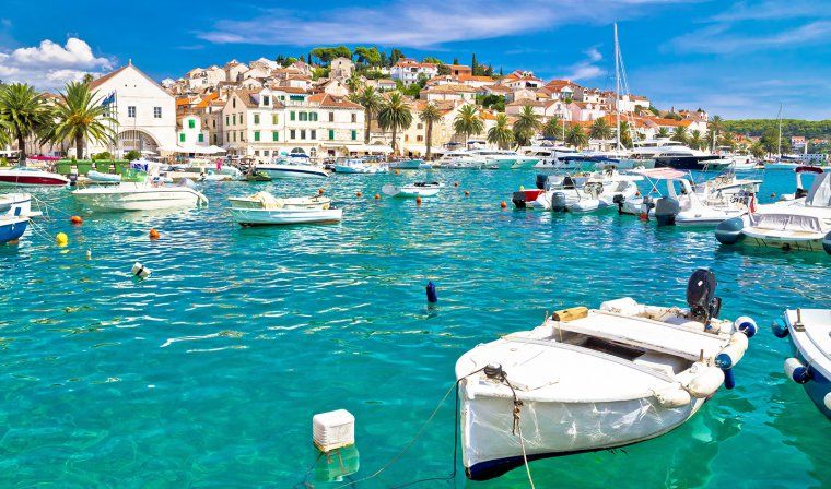 Boats anchored in Hvar harbour with white buildings on a hill in background