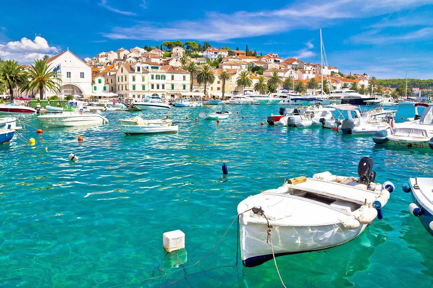 Boats anchored in Hvar harbour with white buildings on a hill in background