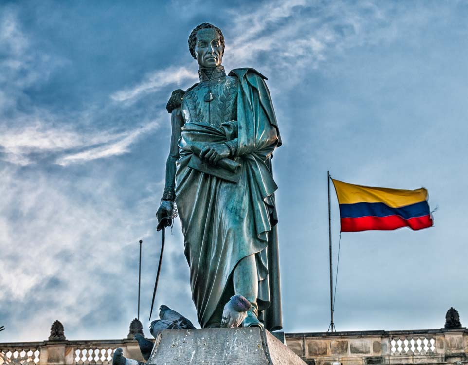 Colombian flag flies behind a statue of Simon Bolivar in Bogota's Plaza Bolivar, located in the Candelaria neighborhood