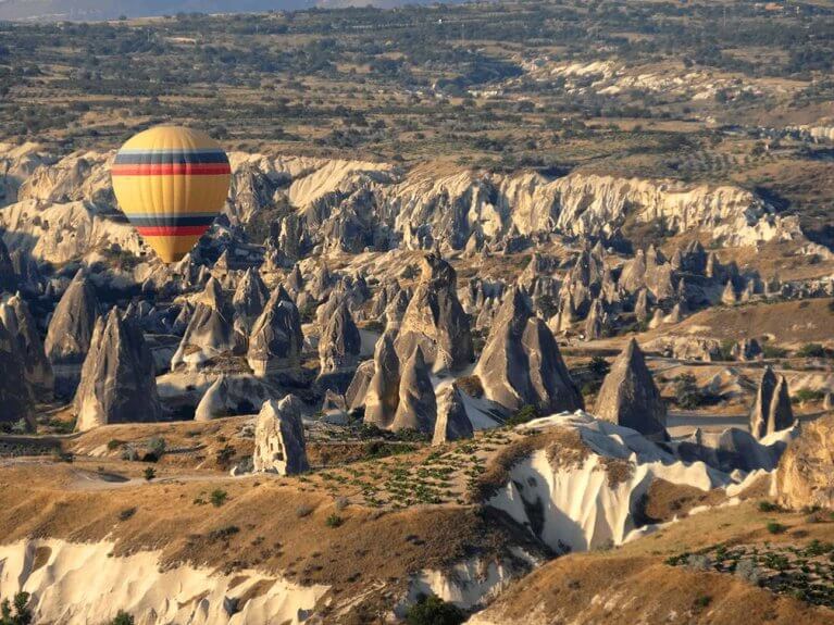 Hot air balloon floats over fairy towers in Cappadocia during luxury Turkey tour
