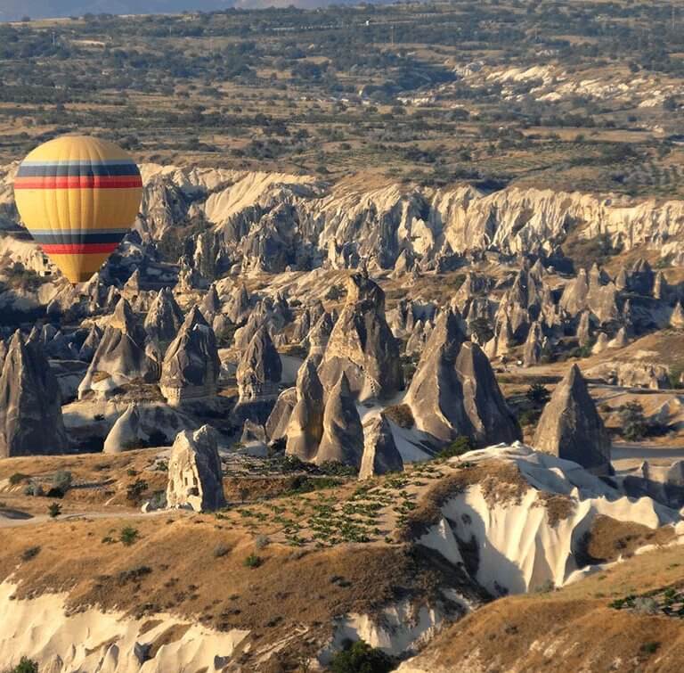 Hot air balloon floats over fairy towers in Cappadocia during luxury Turkey tour