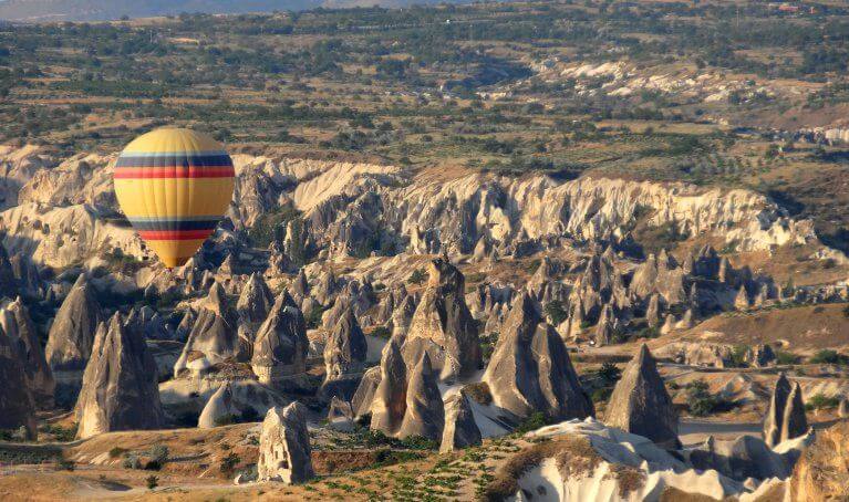 Hot air balloon floats over fairy towers in Cappadocia