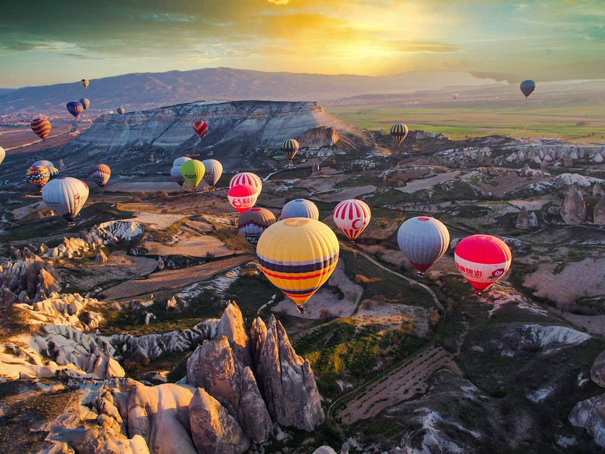 Colorful hot air balloons float over rocky landscape of Cappadocia in Turkey