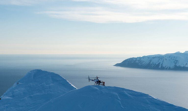 Helicopter hovering above snowy mountains and inlets of Iceland