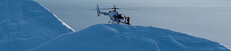 Helicopter hovering above snowy mountains and inlets of Iceland