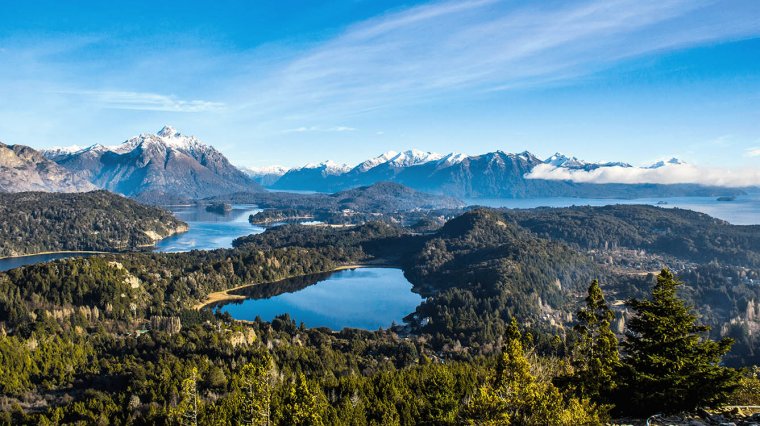 View of Nahuel Huapi Lake surrounded by alpine forest and snow capped mountains