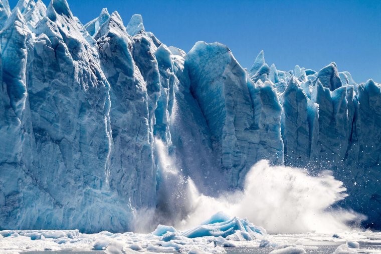 View from water level of a piece of the blue Perito Moreno Glacier falling into Lago Argentino causing a huge splash