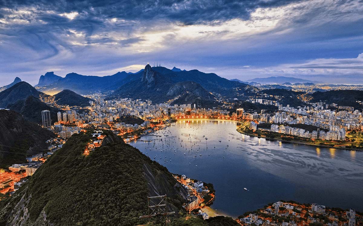 Looking down over Sugarloaf Mountain, bay, and Rio de Janeiro with city lights at sunset