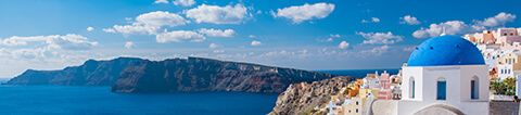 View of Santorini's blue domed white buildings, the Aegean sea, and rocky cliffs