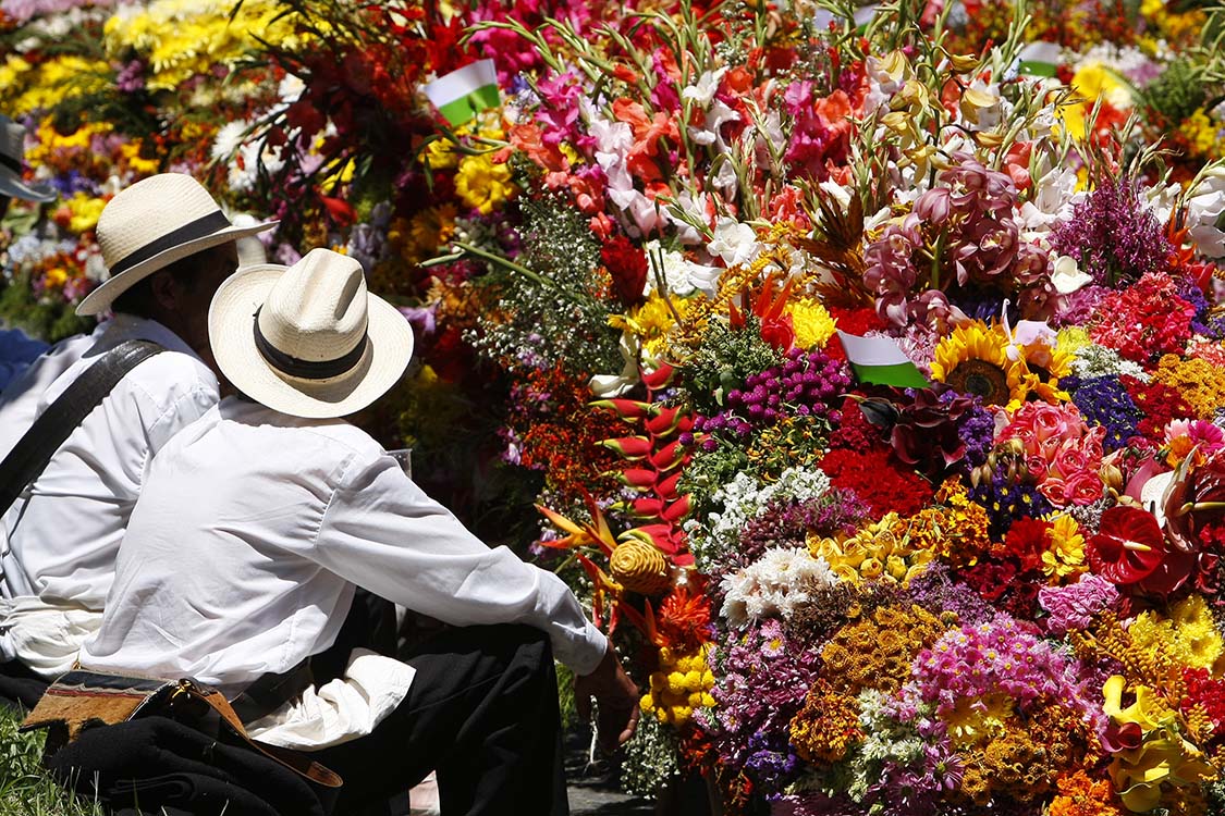 Silleteros in Medellin sitting in front of their flower arrangements