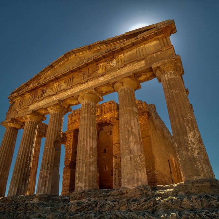 Looking up at columns of a ruined Roman temple in Valley of the Temples on a sunny day in Agrigento, Italy
