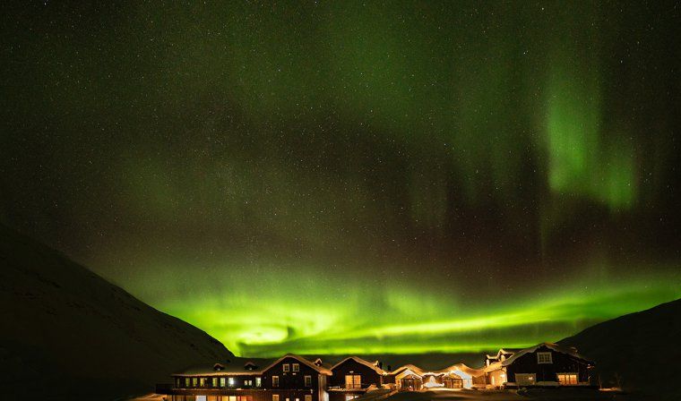 Starry night sky lit up by the Aurora Borealis above Deplar Farm in Northern Iceland