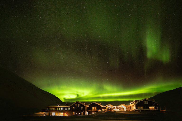 Starry night sky lit up by the Aurora Borealis above Deplar Farm in Northern Iceland