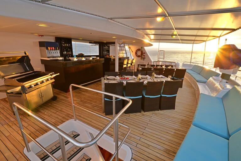 Dining area with tables, bar, and grill on luxury yacht sailing in the Galapagos islands