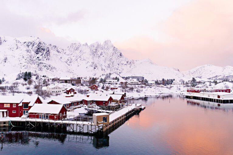 Fisherman's cabins covered in snow in Lofoten, Norway at dawn