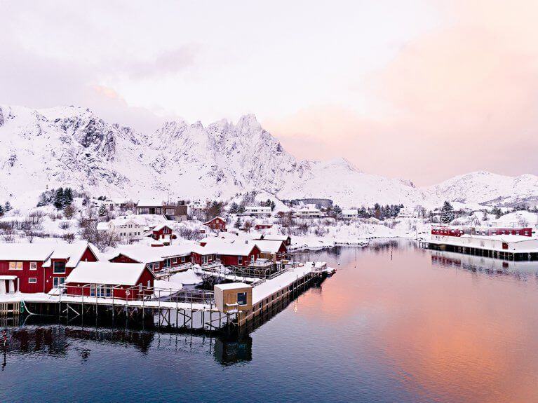 Fisherman's cabins covered in snow in Lofoten, Norway at dawn