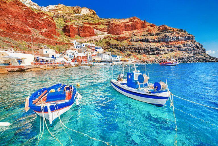 Small fishing boats docked by a village in the Aegean sea