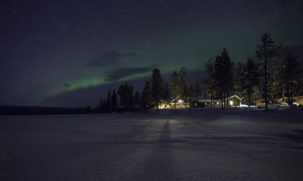 Exterior view of Fjellborg Arctic Lodge in Kiruna, with Northern Lights in the sky above