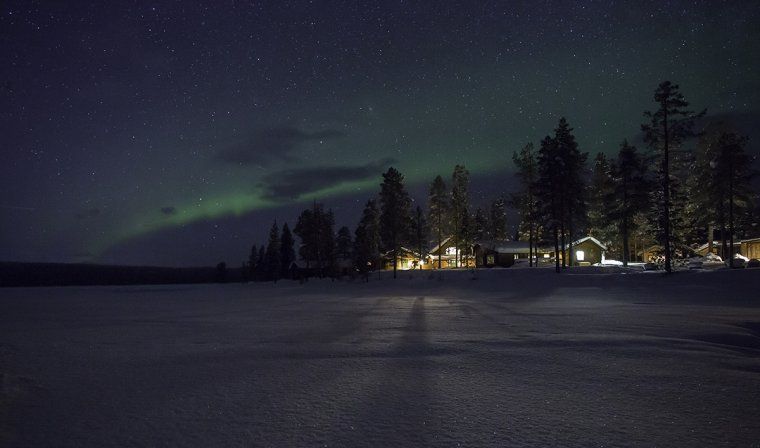 Exterior view of Fjellborg Arctic Lodge in Kiruna, with Northern Lights in the sky above