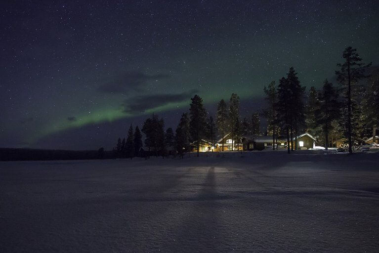 Exterior view of Fjellborg Arctic Lodge in Kiruna, with Northern Lights in the sky above
