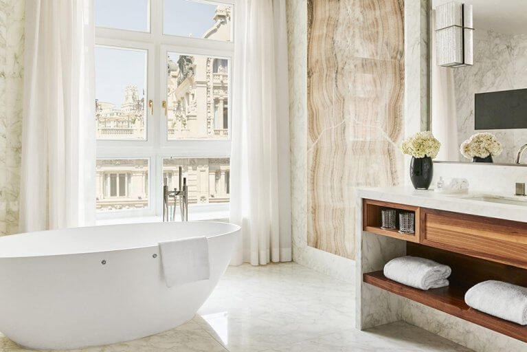 Luxury ensuite bathroom with marble floor and walls and large bathtub at the Four Seasons luxury hotel in Madrid, Spain