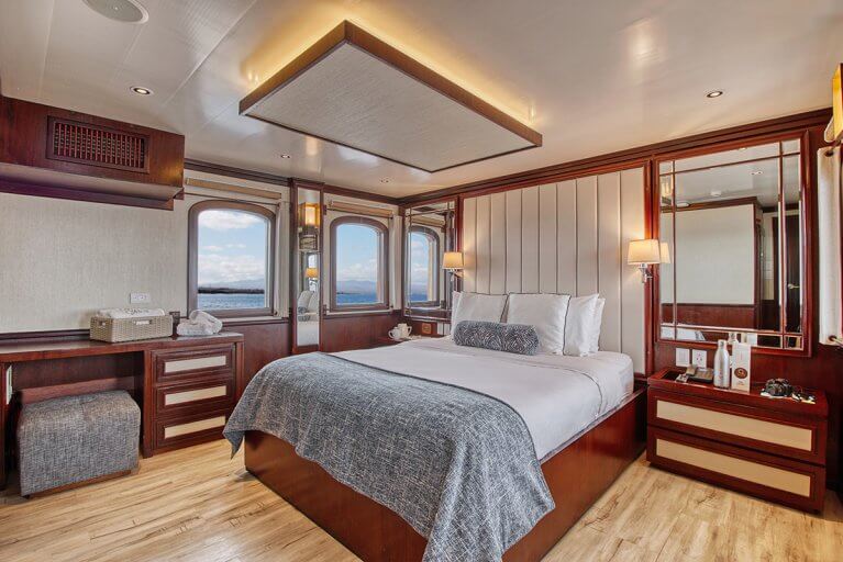 Spacious cabin with bed and desk on luxury yacht sailing in the Galapagos Islands