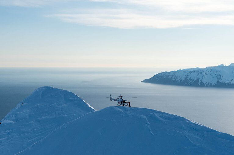 Helicopter hovering above snowy mountains and inlets of Iceland