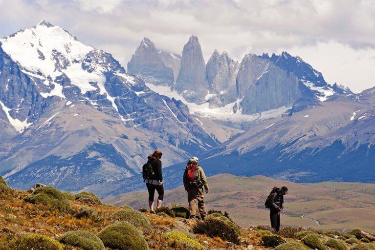 Three people enjoying a private hiking tour with mountains in the distance in Torres del Paine National Park