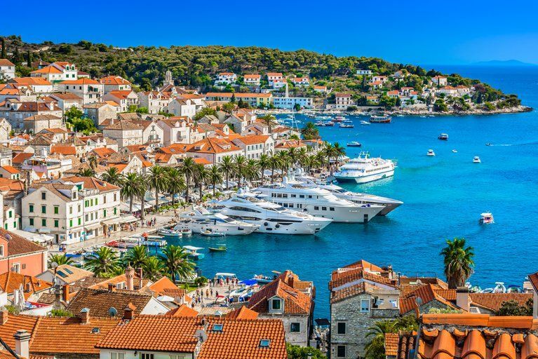 Luxury yachts docked in Hvar, Croatia with red roofed buildings in town