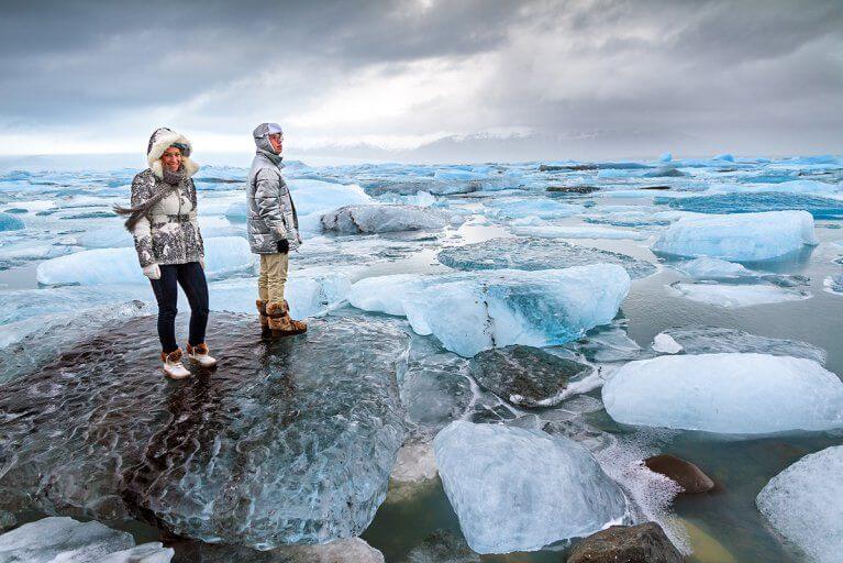 Couple standing on a floating iceberg in Jokulsarlon lagoon