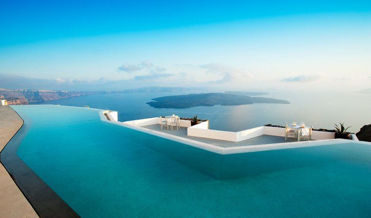 Outdoor infinity pool at Grace luxury hotel with view of Aegean sea and cliffs in the distance