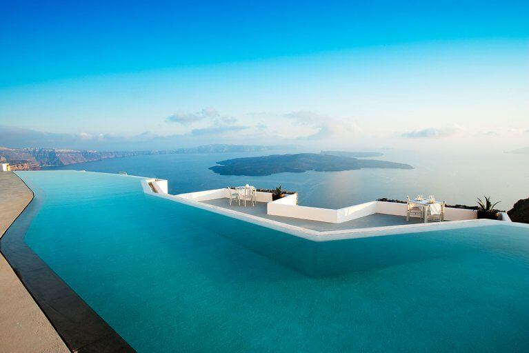Outdoor infinity pool at Grace luxury hotel with view of Aegean sea and cliffs in the distance