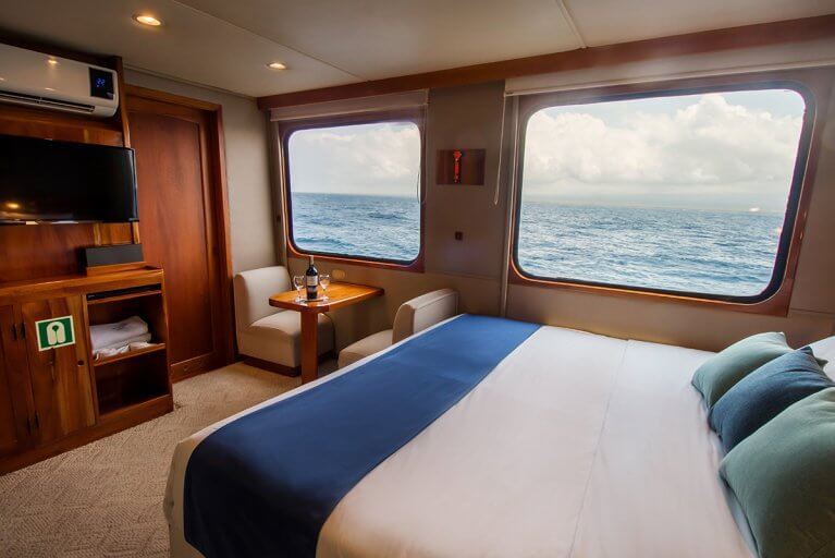 Cabin with large bed, TV, and two large windows on luxury yacht during Galapagos Islands cruise