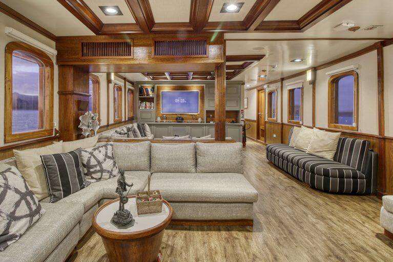 Large interior saloon with several sofas and large TV on a private luxury yacht sailing in the Galapagos Islands