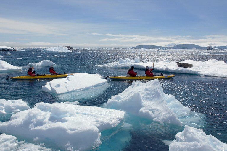 Kayaking excursion through the icebergs of Antarctica, with seals resting in the sun