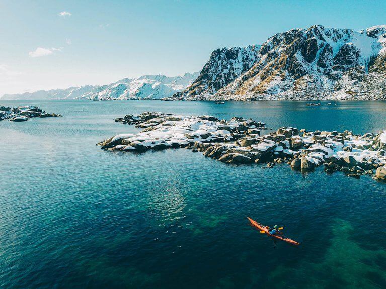 Winter kayaking excursion near snowy mountains in Lofoten
