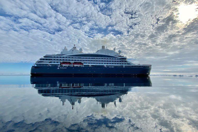 The Commandant Charcot cruisint in Antarctica, with the sky reflected in the water below