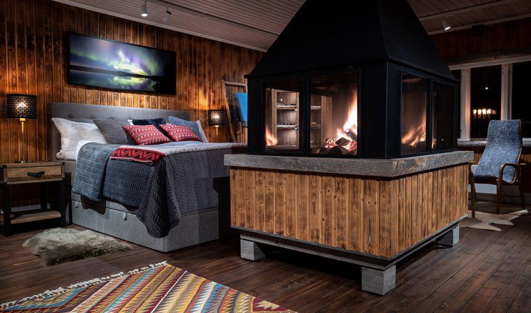 Interior view of a bedroom with fireplace in a luxury wilderness lodge in Lapland, Sweden