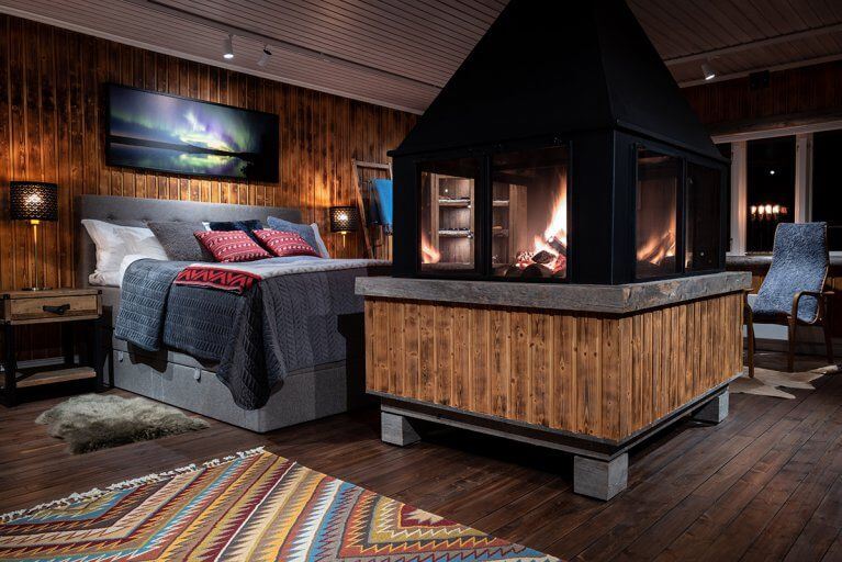 Interior view of a bedroom with fireplace in a luxury wilderness lodge