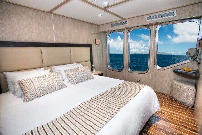 Cabin with large bed and three windows on a luxury yacht sailing in the Galapagos islands