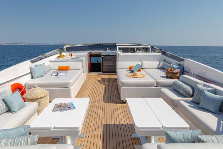 Open sundeck with sun loungers on private yacht charter sailing in Aegean sea with islands in the distance