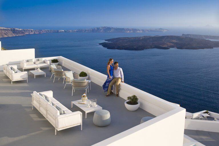 Couple enjoys view of sea and islands from Grace hotel terrace in Santorini