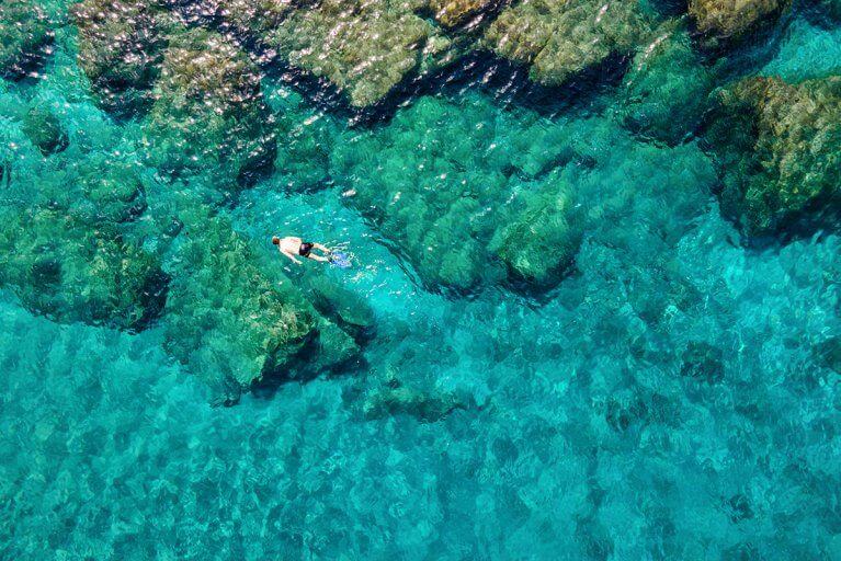 Aerial view of man snorkeling in clear blue waters of the Aegean sea