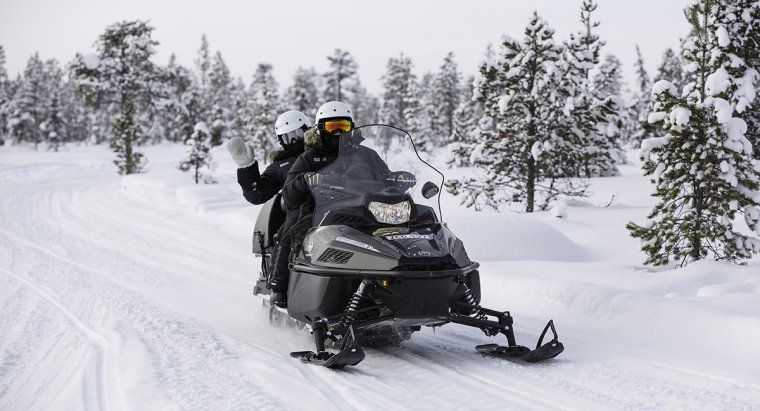 Woman waving during a snowmobiling excursion